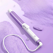 Ferro arricciacapelli viola su sfondo lilla, design elegante, cavo girevole, ideale per ricci definiti e styling professionale.