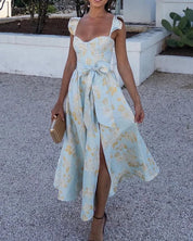 Abito estivo donna elegante, floreale azzurro e giallo, con spacco e fiocco in vita. Perfetto per cerimonie e eventi all'aperto.