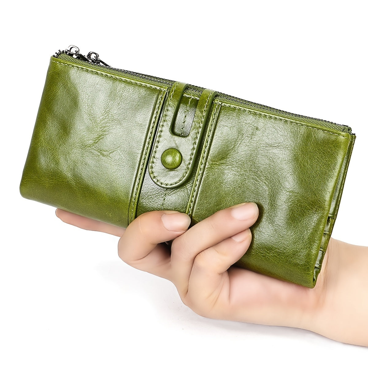 Portafoglio in pelle verde lucida tenuto in mano, con chiusura a bottone e cerniera. Accessorio moda elegante e pratico per donna.