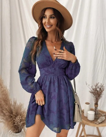 Donna con abito blu a fiori, maniche lunghe, cappello beige, borsa a tracolla, sfondo bianco. Moda femminile elegante, abbigliamento autunnale.