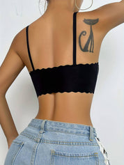 Donna con top nero senza schienale, tatuaggio di gatto stilizzato sulla spalla, jeans a vita alta. Moda estiva, abbigliamento casual femminile.