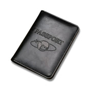 Custodia passaporto in pelle nera con incisione "Passport" e simbolo del globo, accessorio da viaggio elegante e protettivo.