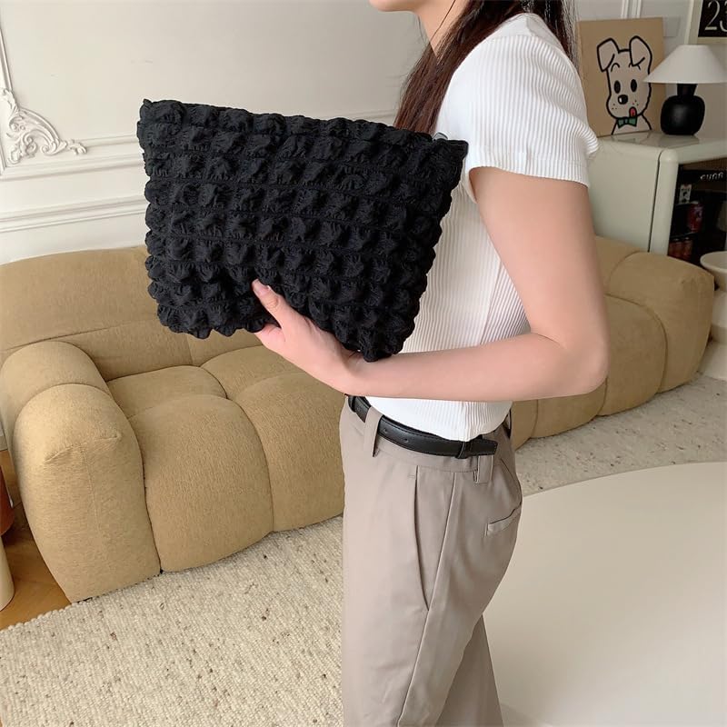 Donna con borsa a mano nera lavorata a maglia, indossa maglietta bianca e pantaloni beige, in salotto moderno. Accessori moda, stile casual chic.