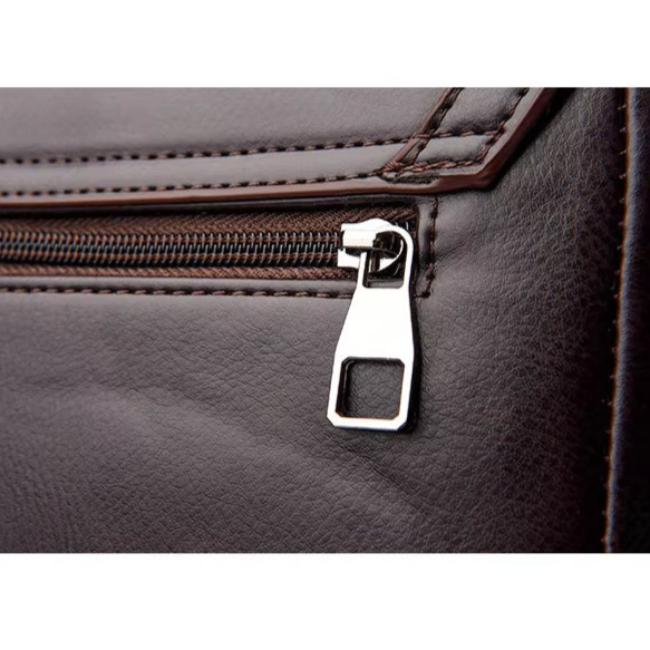 Primo piano di una cerniera su borsa in pelle marrone, dettaglio elegante e di alta qualità, accessorio moda uomo, chiusura resistente.