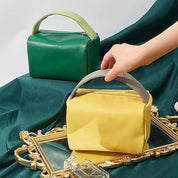 Borse a mano in pelle verde e gialla su sfondo elegante con cornice dorata. Design moderno, accessori moda, stile contemporaneo.