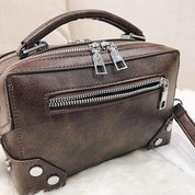 Borsa a tracolla in pelle marrone con cerniere argentate, design moderno e manico superiore. Accessorio moda elegante per donna.