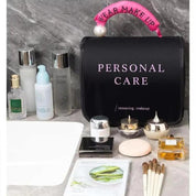 Set di prodotti per la cura della pelle su un piano in marmo, include creme, lozioni, pennelli trucco e una borsa nera con scritta "Personal Care".
