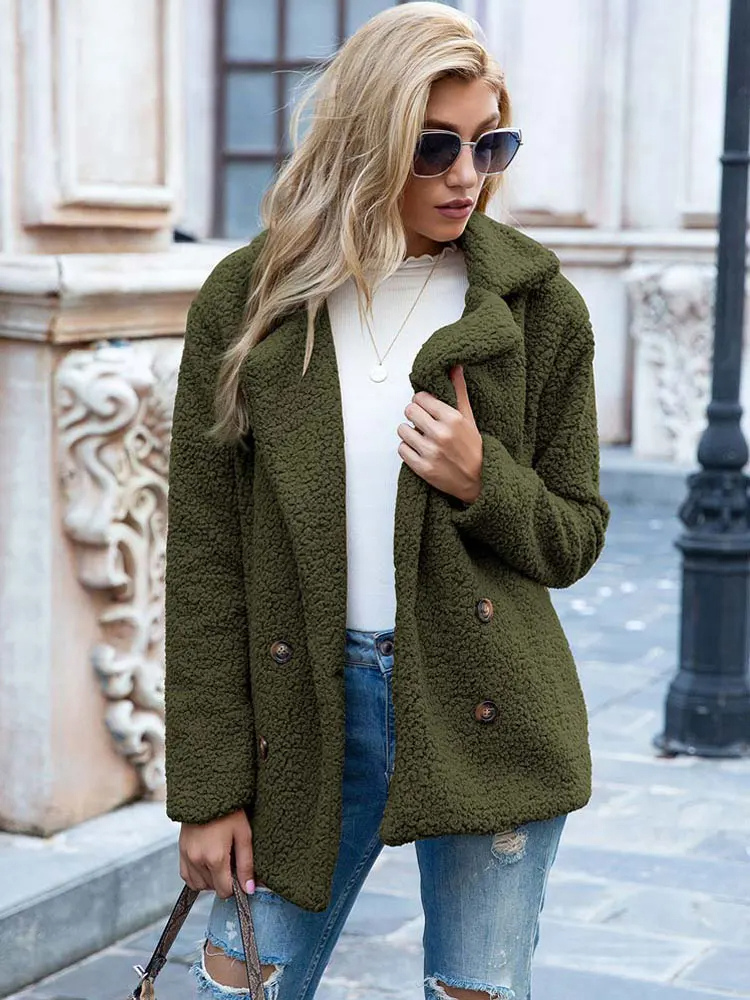 Donna con cappotto verde oliva in pile, occhiali da sole, jeans strappati, maglia bianca, posa urbana. Moda autunnale casual elegante.
