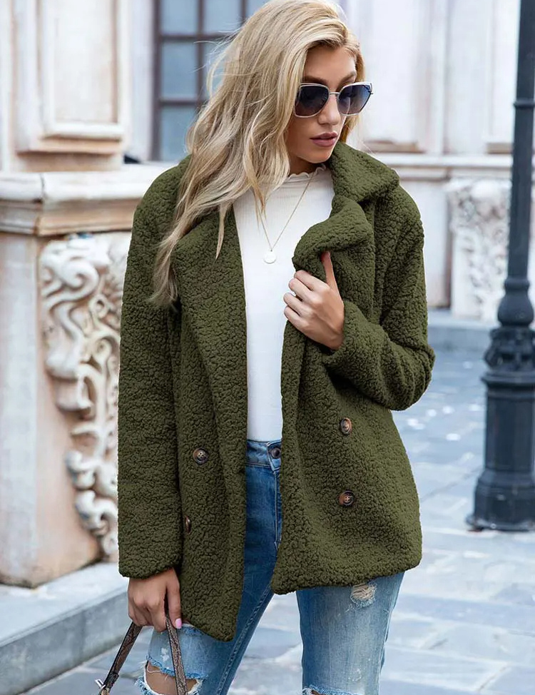 Donna con cappotto verde oliva in pile, occhiali da sole, jeans strappati, maglia bianca, posa urbana. Moda autunnale casual elegante.