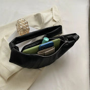 Marsupio nero in pelle su tessuto beige, aperto con smartphone, portafoglio e accessori visibili. Design elegante, moda accessori donna.
