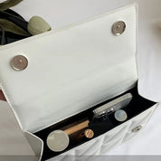 Borsa a tracolla bianca aperta con chiusura magnetica, contenente smartphone, rossetto e profumo. Accessorio moda elegante e pratico per donna.