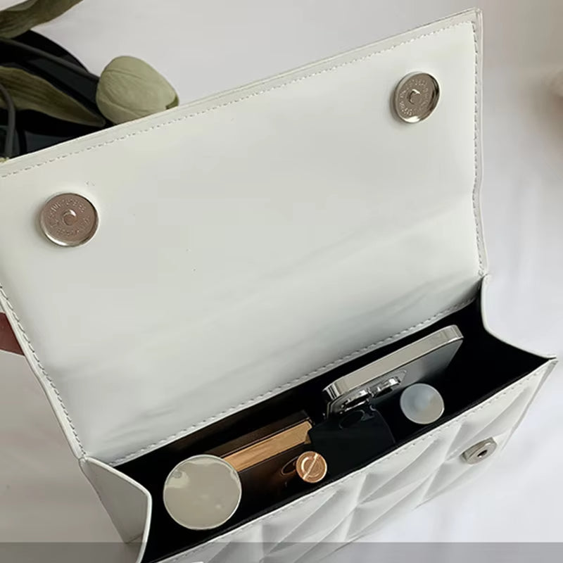 Borsa a tracolla bianca aperta con chiusura magnetica, contenente smartphone, rossetto e profumo. Accessorio moda elegante e pratico per donna.