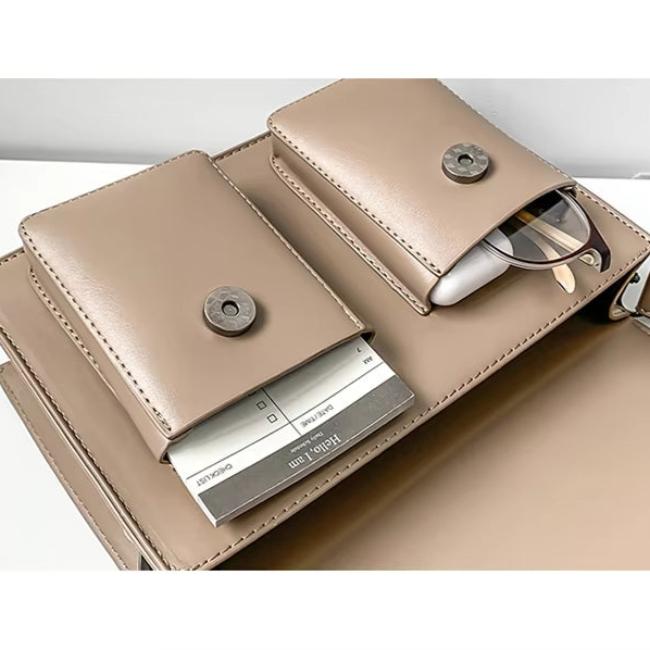 Borsa beige in pelle con tasche interne, occhiali e blocco note. Elegante accessorio moda donna, ideale per ufficio e viaggi.
