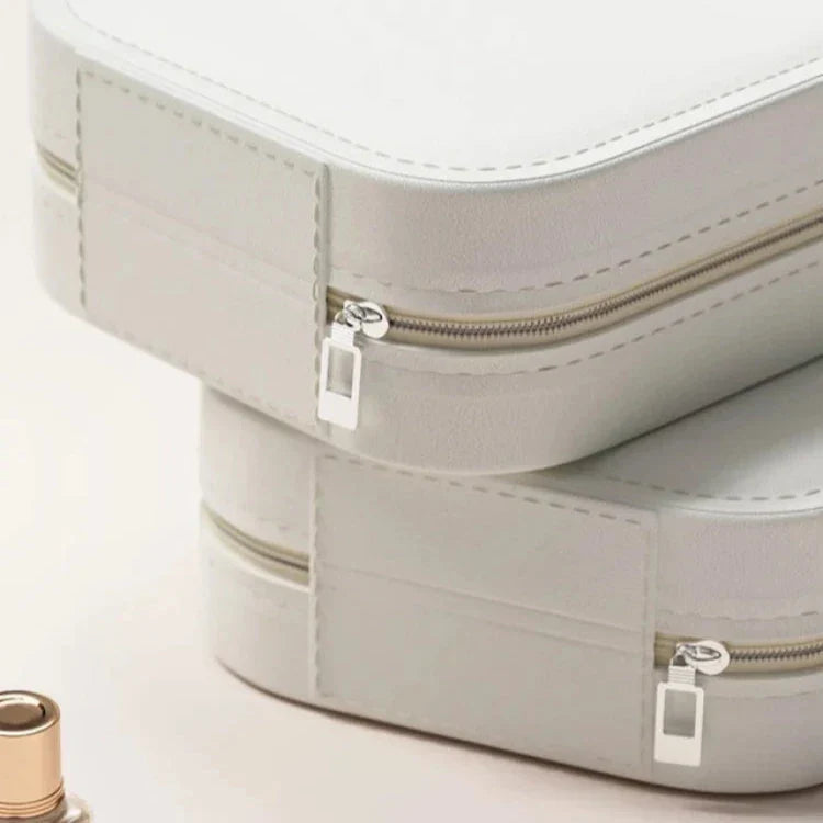 Due astucci in pelle bianca con cerniere argentate, design elegante e minimalista, ideali per cosmetici o accessori da viaggio.