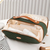 Borsa da toilette verde intrecciata con manico in pelle marrone, scomparti multipli, ideale per organizzare cosmetici e accessori da viaggio.