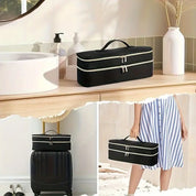 Elegante beauty case nero con doppia zip e manico, posizionato su mobile bagno e valigia. Ideale per viaggi, organizzazione cosmetici e accessori.