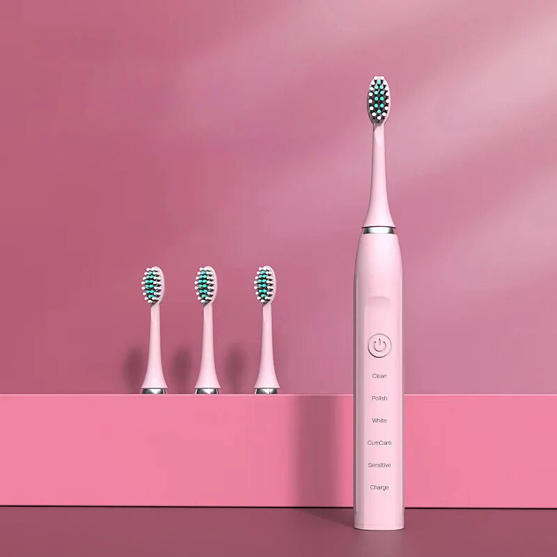 Spazzolino elettrico rosa con tre testine di ricambio su sfondo rosa. Design elegante, tecnologia avanzata, cura dentale efficace.