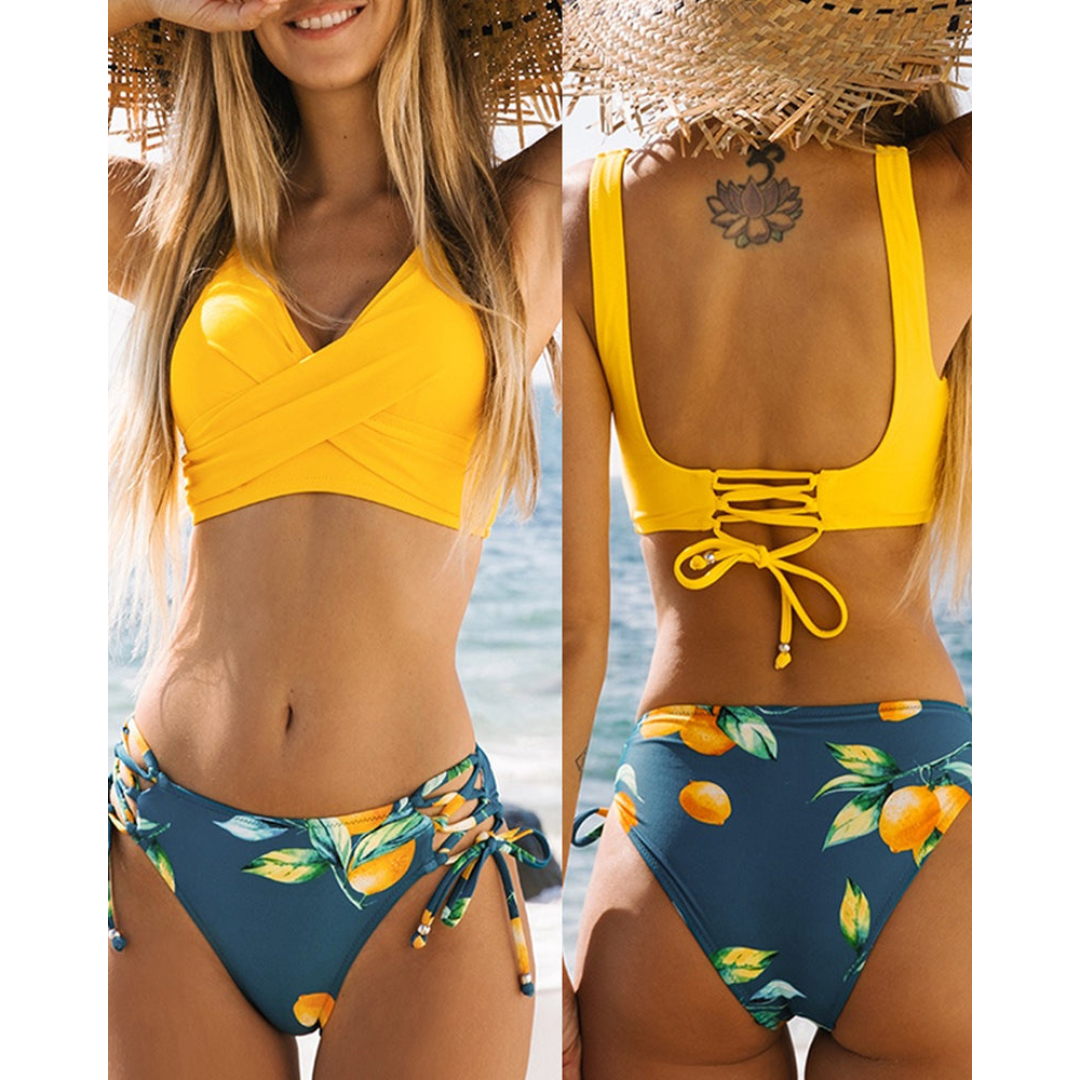 Bikini donna giallo e blu con stampa agrumi, top incrociato e slip con laccetti. Costume da bagno estivo, moda mare, spiaggia.