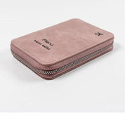 Portafoglio da viaggio rosa in pelle sintetica con cerniera, logo "Pioru" e icona aereo. Accessorio elegante e pratico per organizzare documenti.