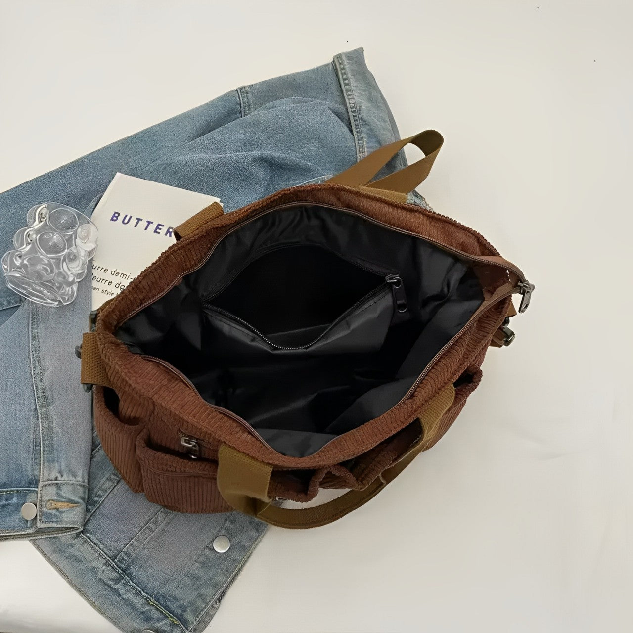 Borsa a tracolla marrone aperta su giacca di jeans, con tasche interne visibili. Accessori moda, stile casual, organizzazione pratica.