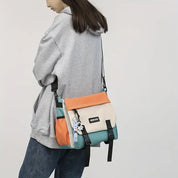 Donna con felpa grigia indossa borsa a tracolla multicolore, design moderno, con portachiavi. Accessorio moda casual, ideale per giovani.