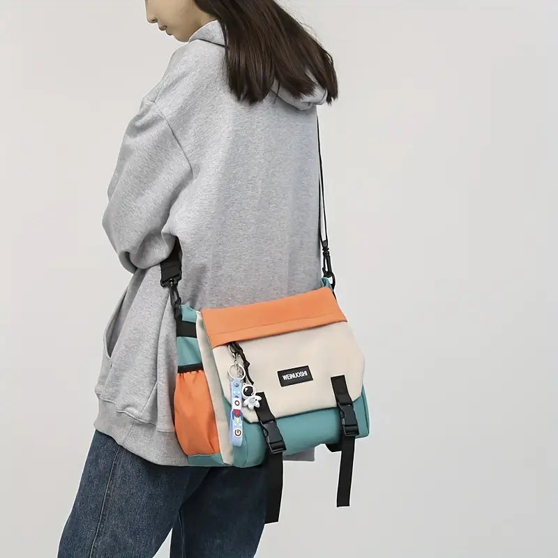 Donna con felpa grigia indossa borsa a tracolla multicolore, design moderno, con portachiavi. Accessorio moda casual, ideale per giovani.