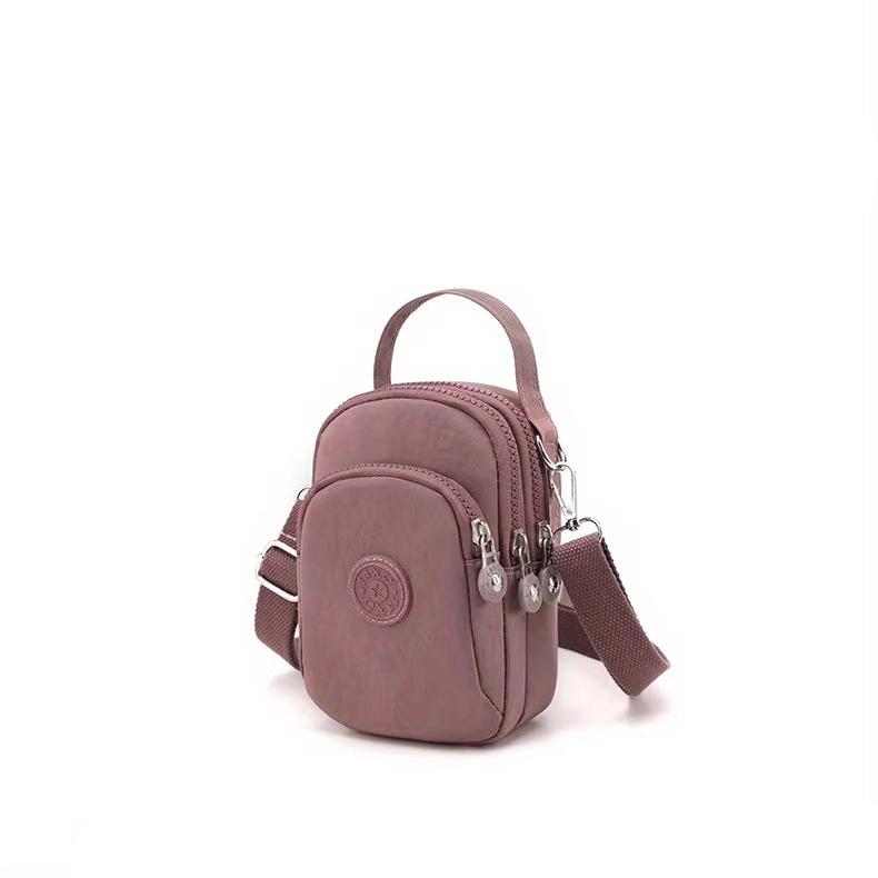 Borsa a tracolla piccola rosa con doppia cerniera, tasche multiple e cinturino regolabile. Design compatto, ideale per viaggi e uso quotidiano.
