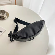 Marsupio nero in pelle su tavolo bianco, design elegante e moderno, perfetto per moda urbana e viaggi. Accessorio versatile e di tendenza.