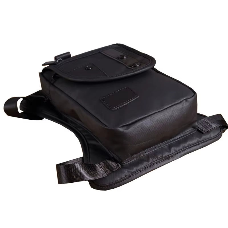 Zaino monospalla nero in pelle sintetica, design moderno, tasca frontale con chiusura a bottone, ideale per viaggi e uso quotidiano.
