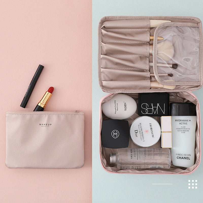 Borsa trucco beige con rossetto rosso, eyeliner e set di cosmetici di lusso, tra cui Chanel e Dior, su sfondo rosa. Organizzazione beauty travel.
