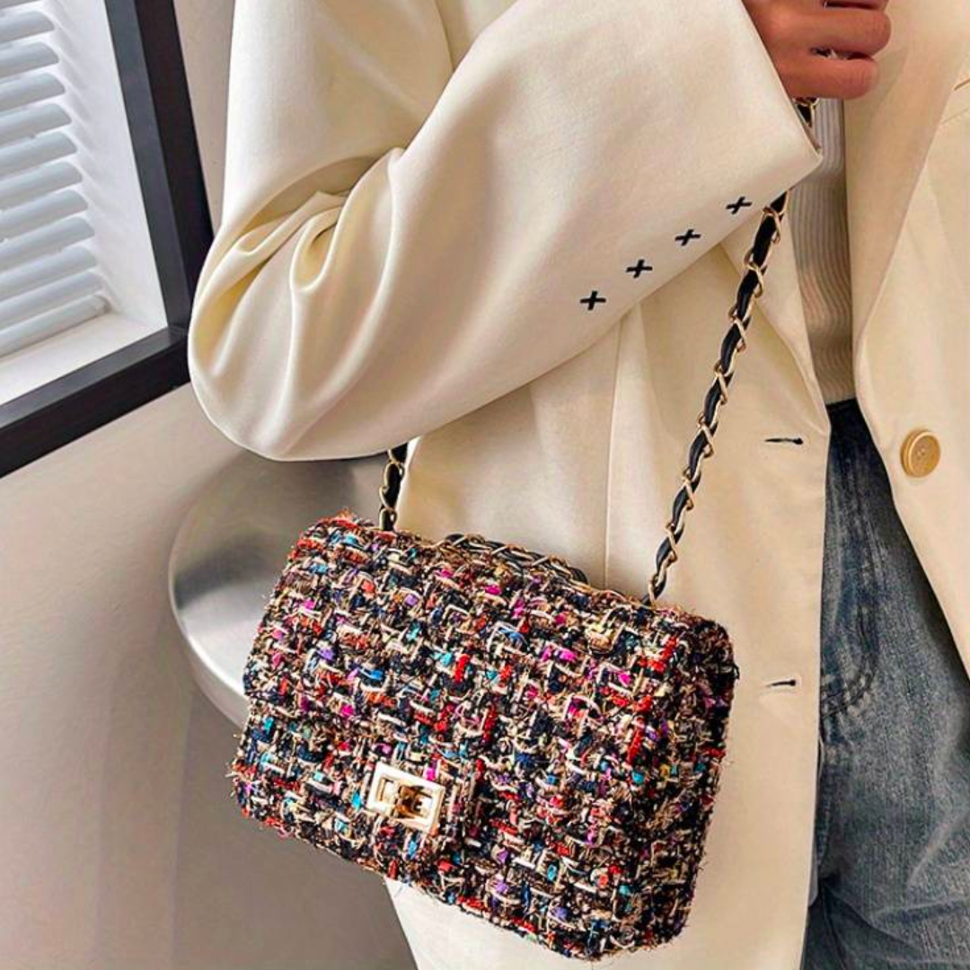 Borsa a tracolla in tessuto multicolore, indossata con giacca bianca. Design elegante, perfetta per moda autunnale e look casual chic.