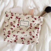 Pochette trucco floreale con rosse rose, contenente pennello, lucidalabbra e carta. Accessorio moda donna, elegante e pratico per cosmetici.
