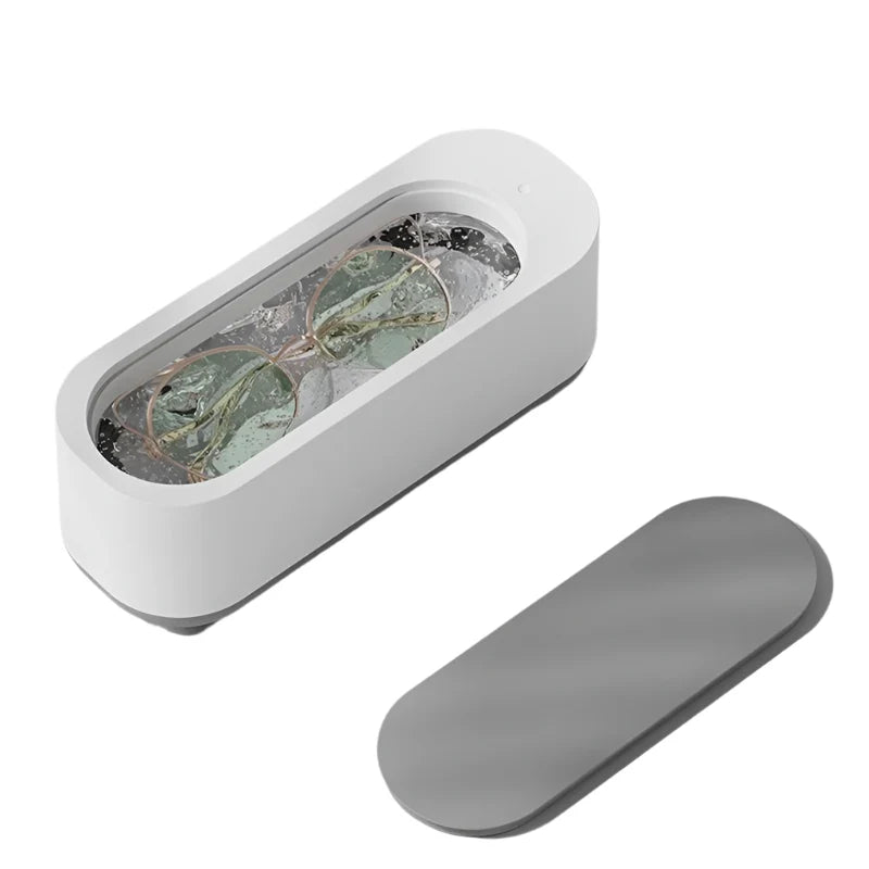 Dispositivo pulizia occhiali ad ultrasuoni bianco, coperchio grigio, design moderno, ideale per lenti e gioielli, tecnologia avanzata, compatto ed efficiente.