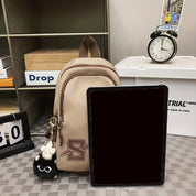 Zaino beige con ciondolo nero, tablet nero, orologio da tavolo e calendario su scaffale. Accessori per ufficio e scuola.