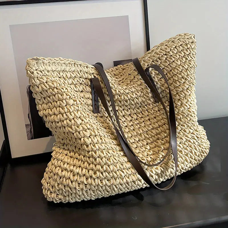 Borsa tote in paglia intrecciata beige con manici in pelle marrone, design estivo elegante, perfetta per spiaggia o shopping.