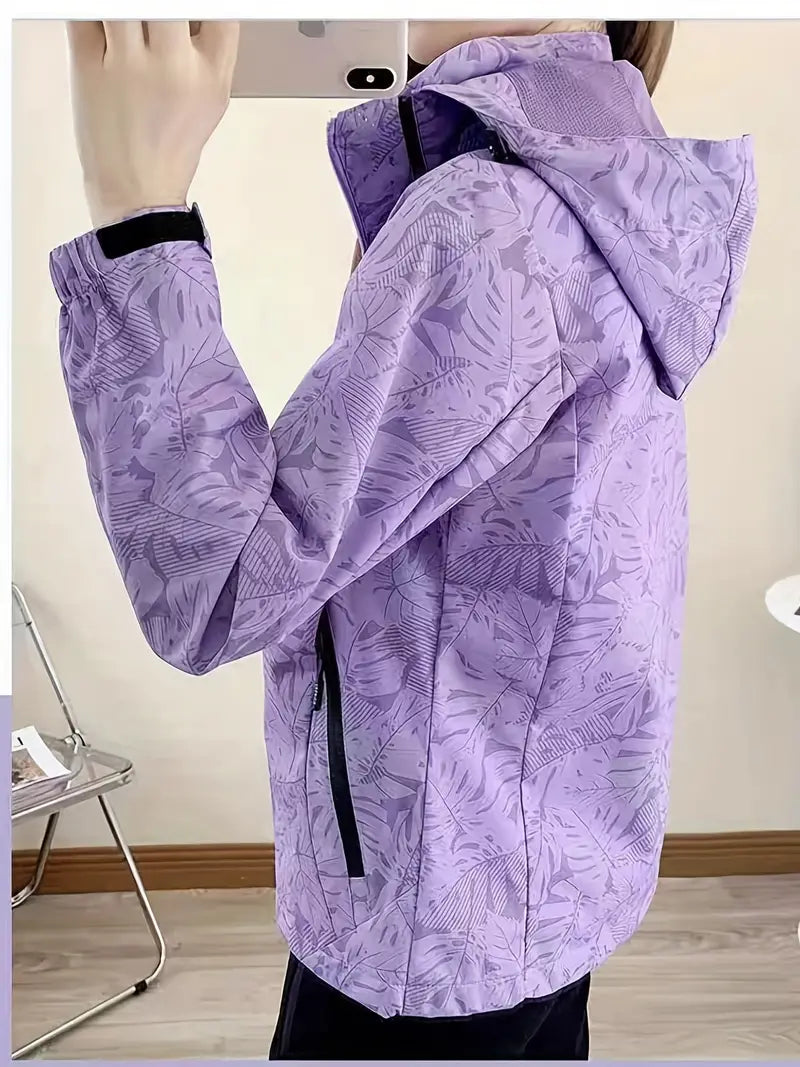 Giacca a vento viola con cappuccio, motivo foglie, chiusura zip nera, design moderno, ideale per attività outdoor. Tessuto leggero e resistente.