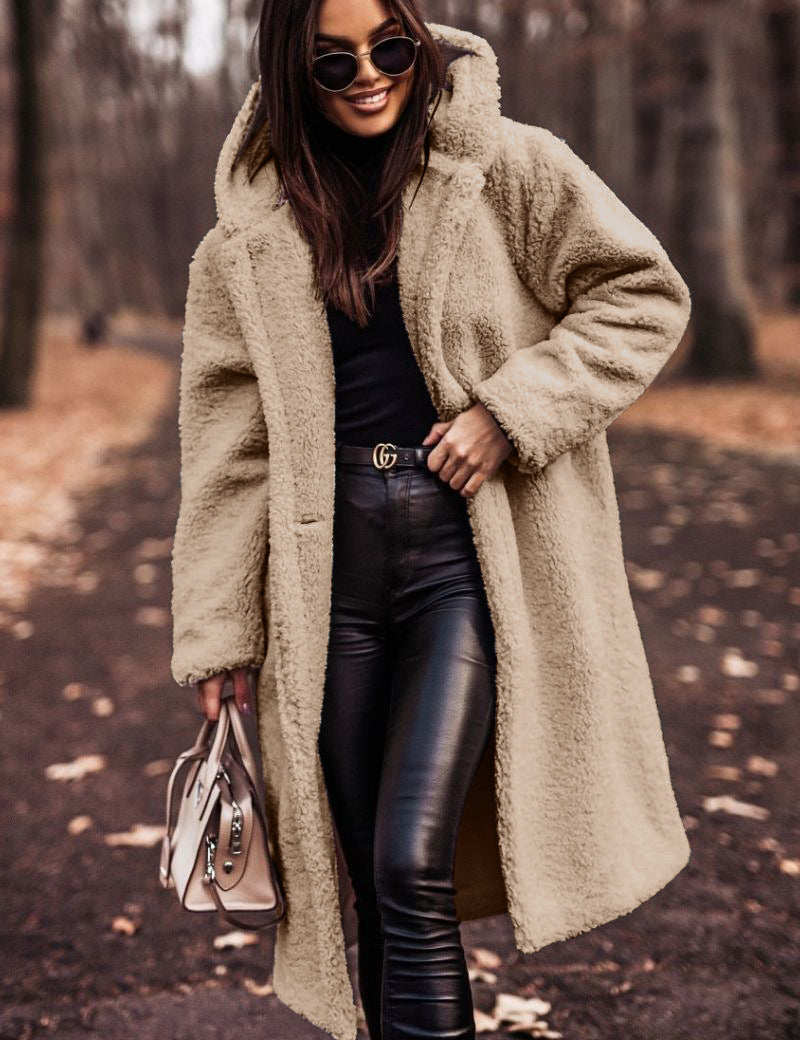 Donna con cappotto teddy beige, occhiali da sole e borsa elegante, passeggia in un parco autunnale. Moda invernale, stile casual chic.