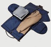 Custodia porta abiti aperta con interno blu a pois, contenente un maglione grigio e un blazer beige. Ideale per viaggi d'affari eleganti.