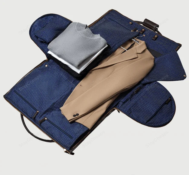 Custodia porta abiti aperta con interno blu a pois, contenente un maglione grigio e un blazer beige. Ideale per viaggi d'affari eleganti.