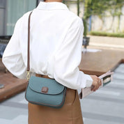 Donna con camicia bianca e borsa a tracolla verde, elegante e moderna, tiene una rivista. Moda femminile, accessori di tendenza, stile urbano.