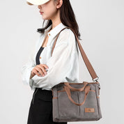 Donna con borsa a tracolla in tela grigia, design casual ed elegante, perfetta per uso quotidiano. Accessorio moda femminile versatile.