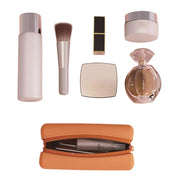 Set di cosmetici con flacone, pennello, rossetto, cipria, profumo e pochette arancione. Accessori trucco eleganti e di lusso.