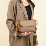 Donna con borsa a tracolla in pelle marrone, elegante e moderna, indossa blazer beige. Accessorio moda femminile, stile casual chic.