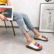 Donna seduta con jeans chiari e sandali estivi multicolore su suola in sughero. Moda casual, calzature estive, stile moderno.