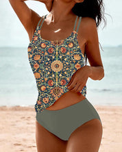 Donna in spiaggia con costume da bagno a due pezzi, top con stampa floreale vintage e slip grigi. Moda mare estiva, abbigliamento da spiaggia elegante.