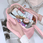 Borsa cosmetica rosa aperta con vari prodotti di bellezza, tra cui creme, flaconi e trucchi. Mani femminili che organizzano il contenuto.