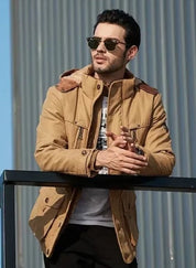 Uomo con giacca beige casual, occhiali da sole, appoggiato a una ringhiera. Moda maschile autunnale, stile urbano, abbigliamento outdoor.