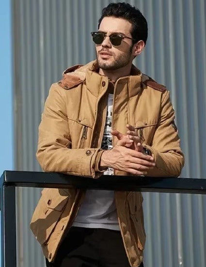 Uomo con giacca beige casual, occhiali da sole, appoggiato a una ringhiera. Moda maschile autunnale, stile urbano, abbigliamento outdoor.