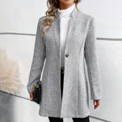 Cappotto donna grigio elegante, monopetto, tessuto a righe, abbinato a dolcevita bianco e pantaloni neri. Look autunnale chic e moderno.