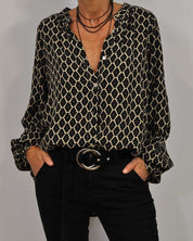 Camicia donna a maniche lunghe con motivo geometrico nero e beige, abbinata a pantaloni neri e cintura con fibbia rotonda. Moda casual elegante.